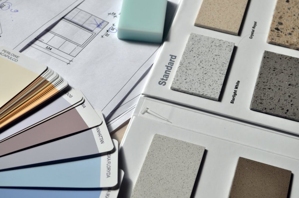 gray-standard-color-book-near-green-eraser-159045 Color palette and material samples for interior renovation projects on a blueprint.